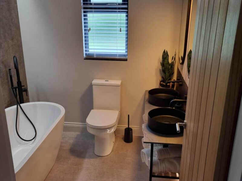 Bathroom with a freestanding bath, twin basins and timber slat panelling