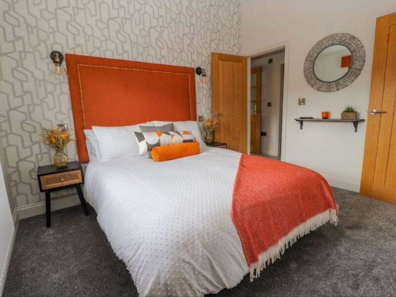 Double bedroom with an upholstered headboard and patterned wallpaper