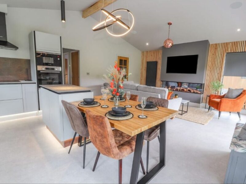 Dining table laid for four, with the kitchen and living area beyond