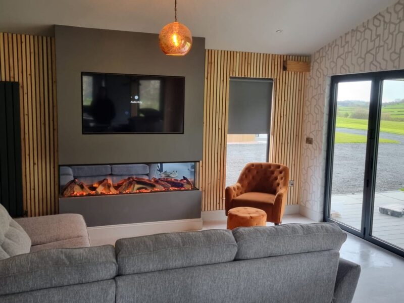 Wall-mounted television above a linear fire, set into a panelled feature wall