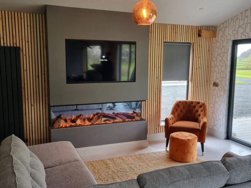 Linear fire and timber slat wall behind a corner sofa and armchair