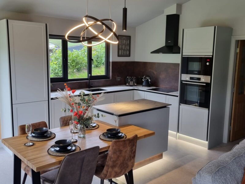 Kitchen with an island, integrated appliances and a dining table alongside