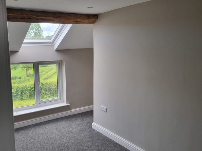 Bedroom under the eaves with a roof window and a window looking out to the fields