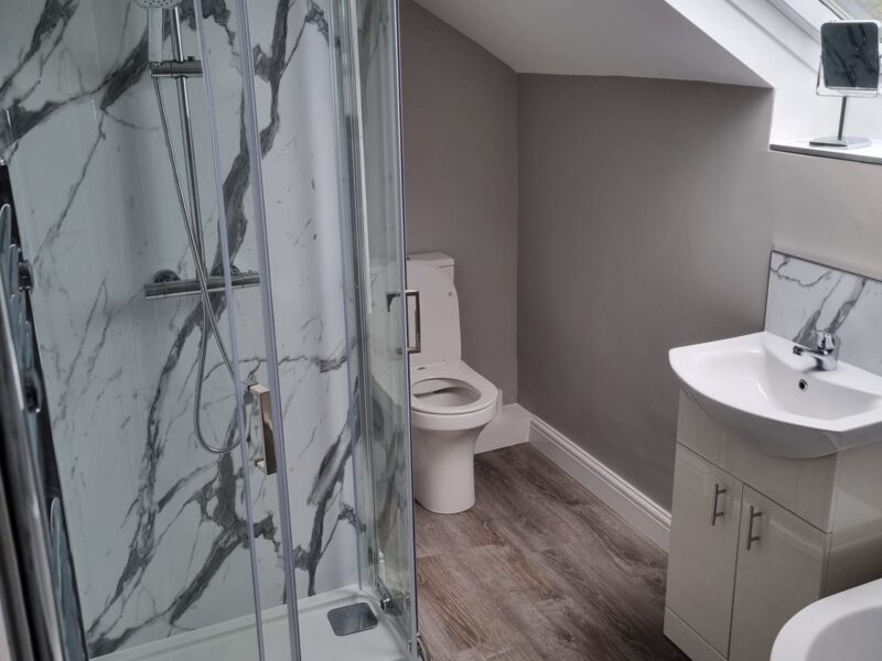 Shower room with a quadrant enclosure, marble-effect panelling and a vanity basin