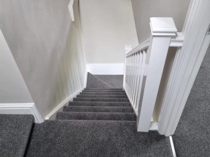 Newly fitted staircase with a painted balustrade and carpeted treads