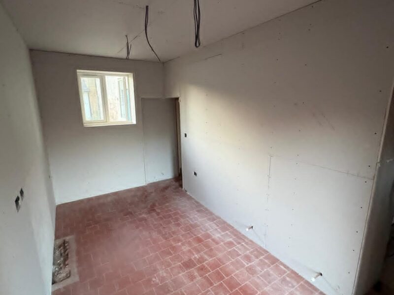Room plasterboarded out, with cabling dropped from the ceiling and the brick floor still exposed